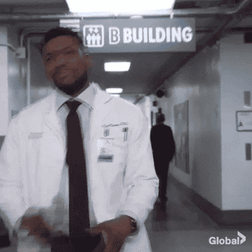 A doctor smiling and walking confidently in a hospital as two other medical professionals follow