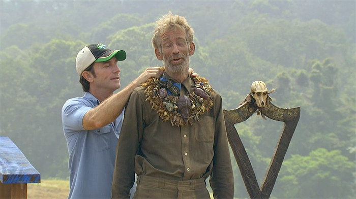 Jeff Probst puts an immunity necklace on Bob Crawley