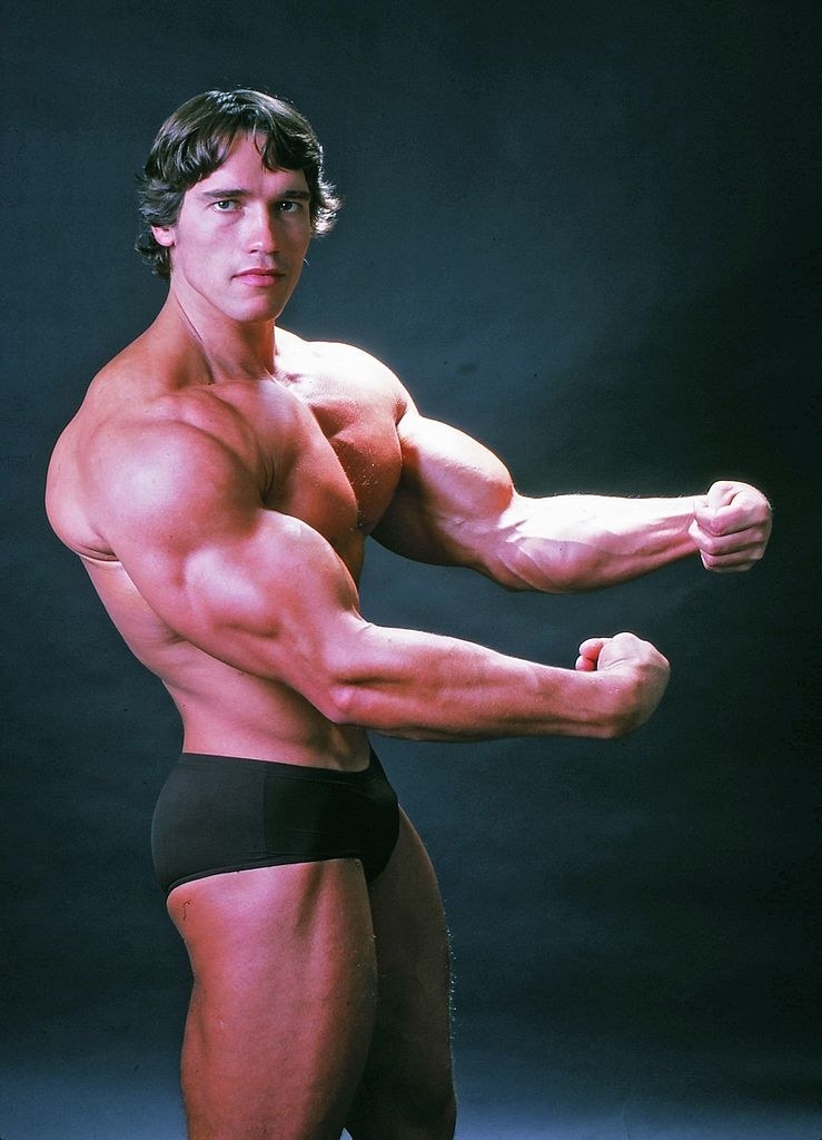 a young Arnold posing to show off his muscles