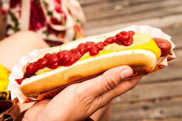 close up of someone holding a hot dog with ketchup and mustard