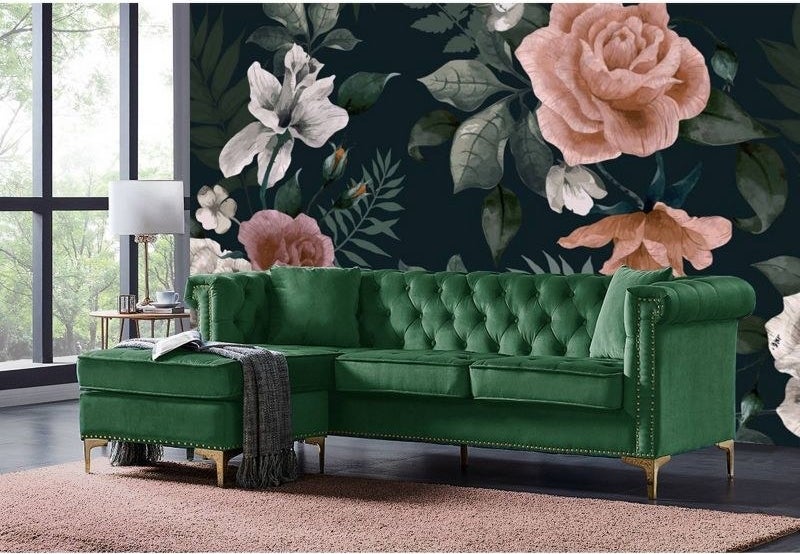 the green sectional in front of a floral accent wall