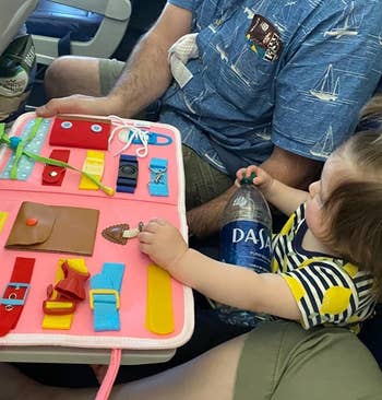 closeup of toddler and parent playing with the board on a plane