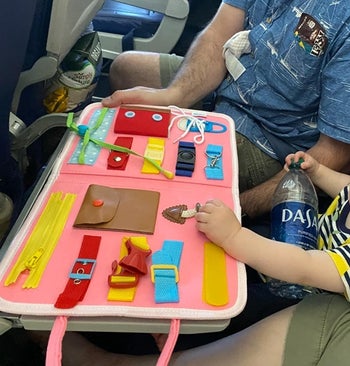 closeup of toddler and parent playing with the board on a plane