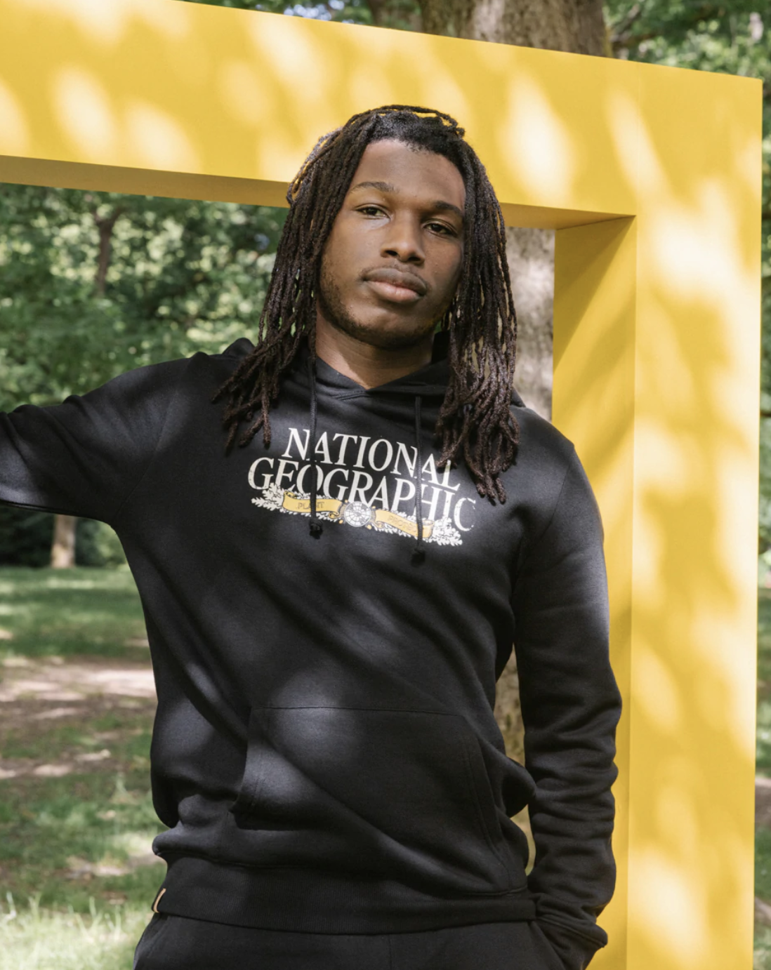 Someone leaning against a structure while wearing a National Geographic sweatshirt.