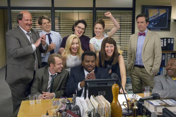 the cast huddled around a desk