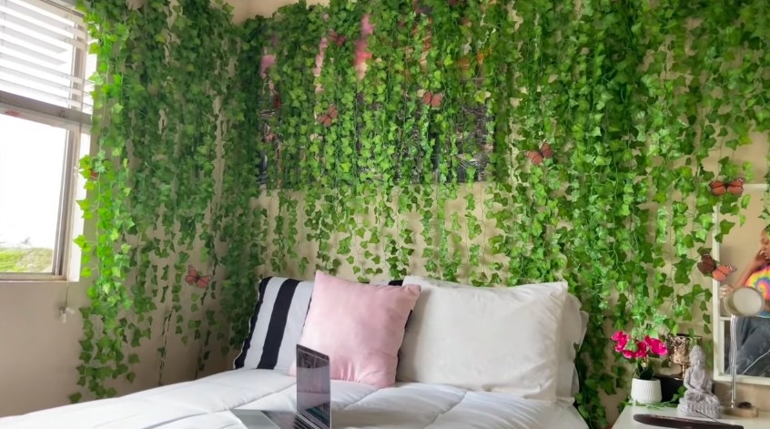 A girly bedroom with tons of fake vines hanging above the bed