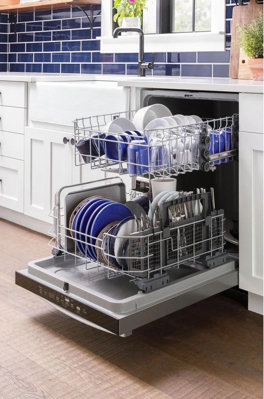 a silver dishwasher with packed dishes, cups, and baking sheet