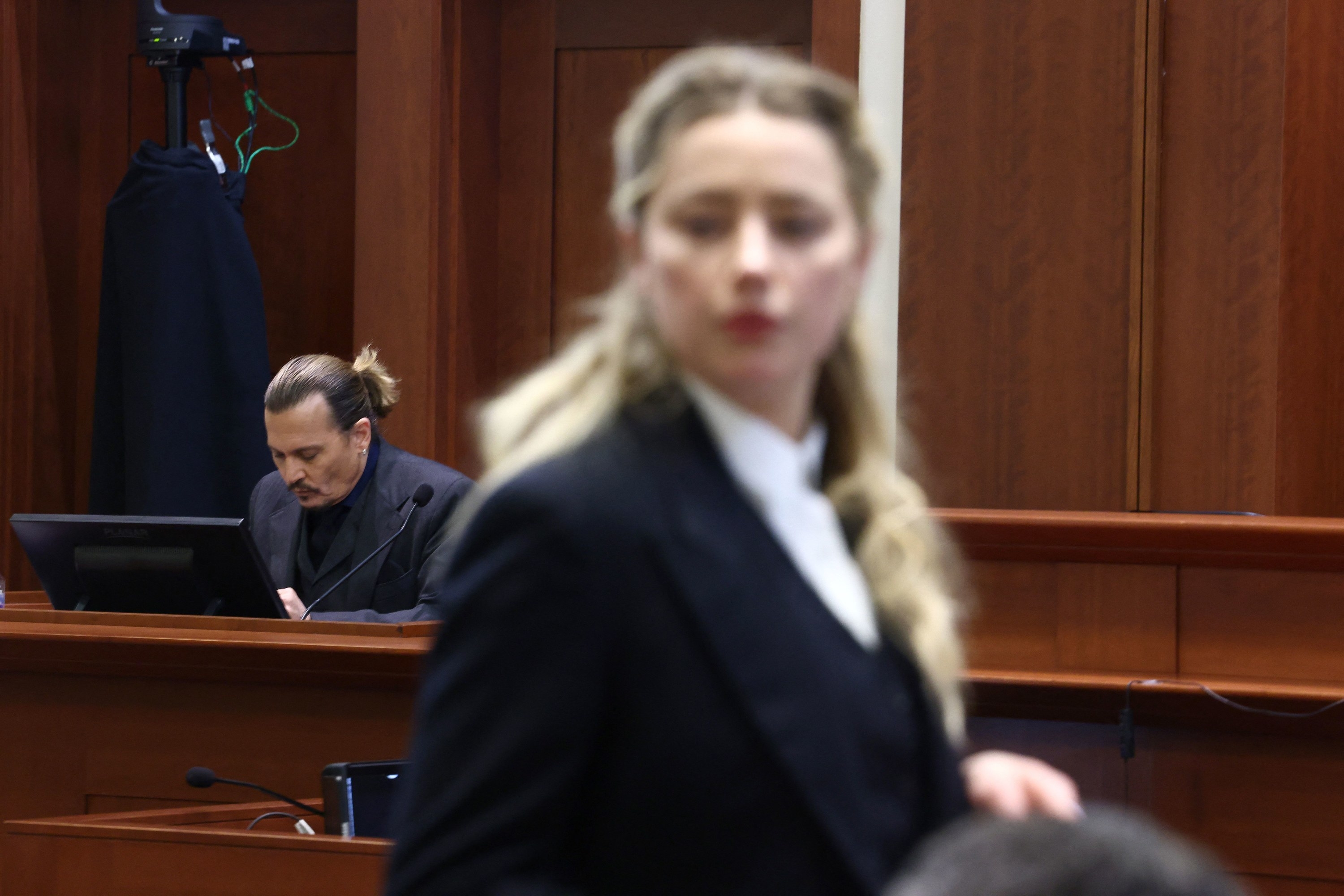 Amber Heard in the foreground, and Johnny Depp in the background, both in court