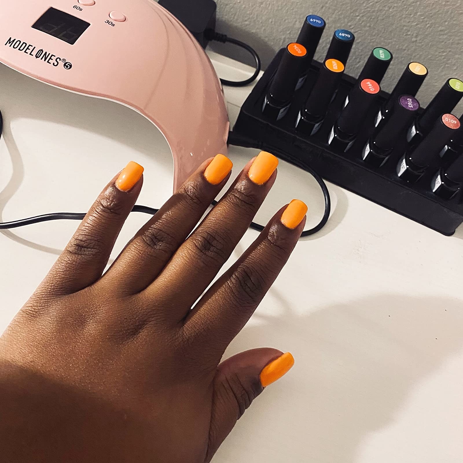 reviewer&#x27;s photo of their bright orange gel manicure completed with the kit
