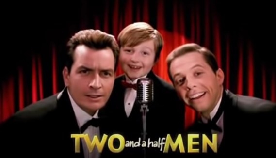 A boy and two men sing into a microphone with the title card &quot;Two and a half Men&quot;