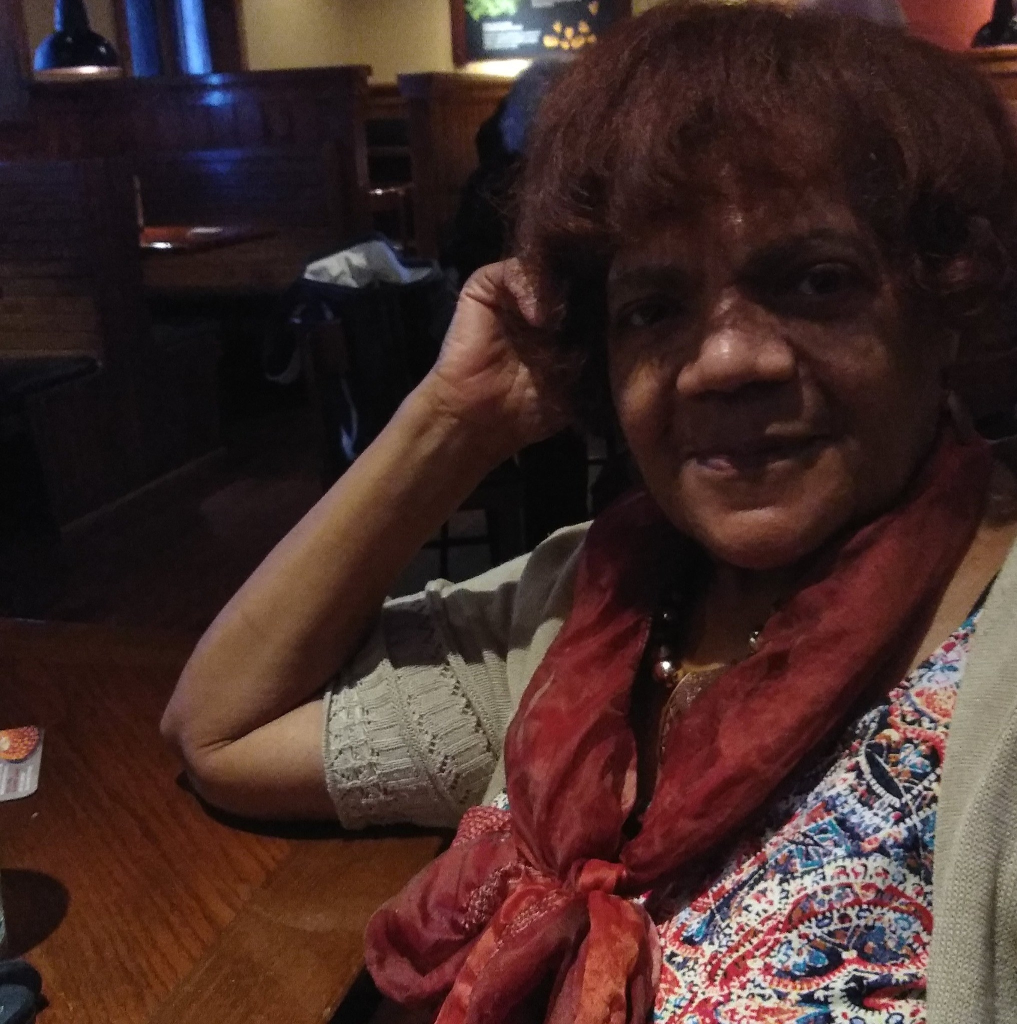 A smiling woman leans her elbow on a table