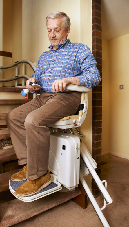 An older gentleman using a stairlift chair.