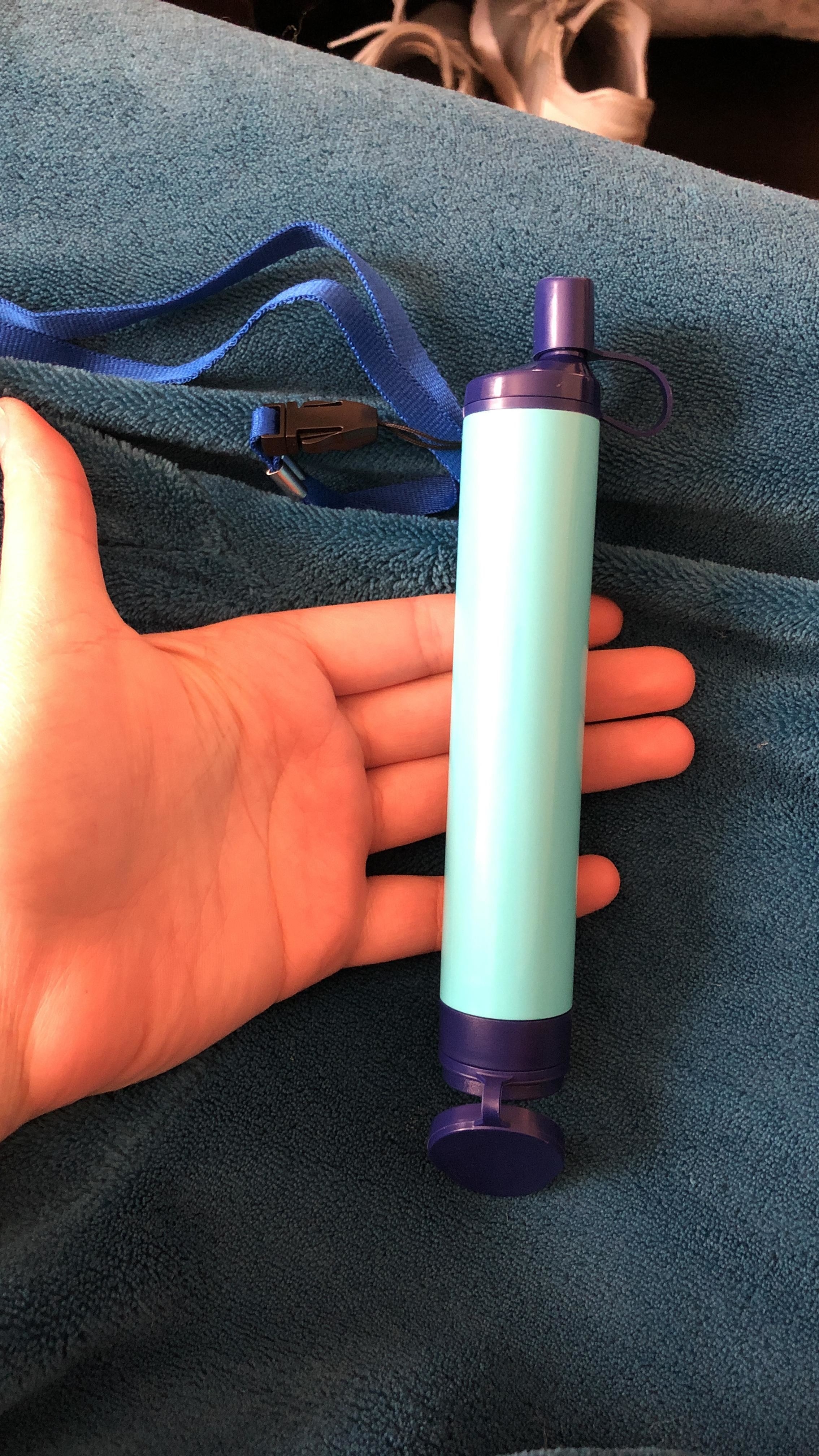 reviewer holding one of the water filtering straws in their hand
