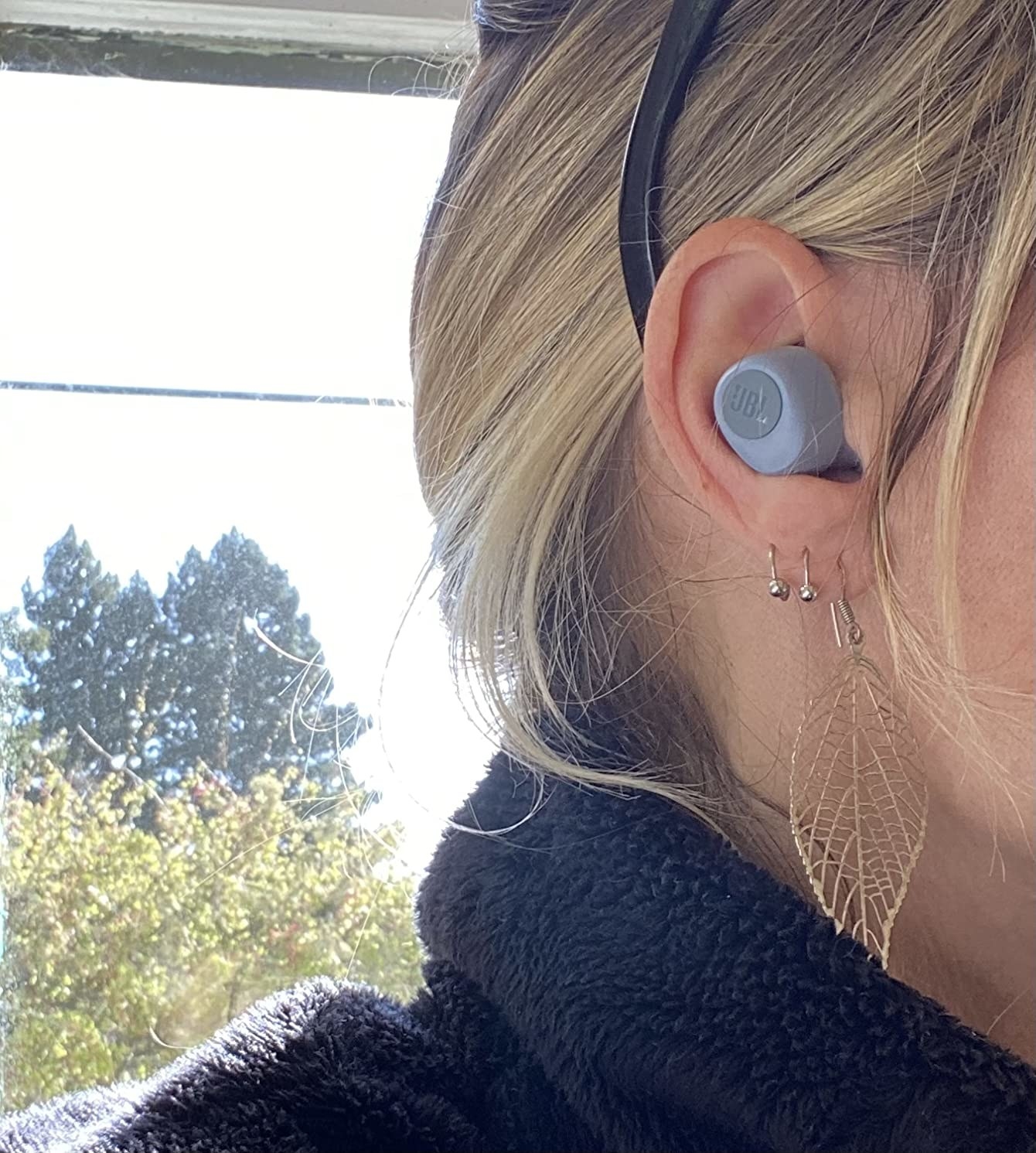 reviewer wearing the blue earbud