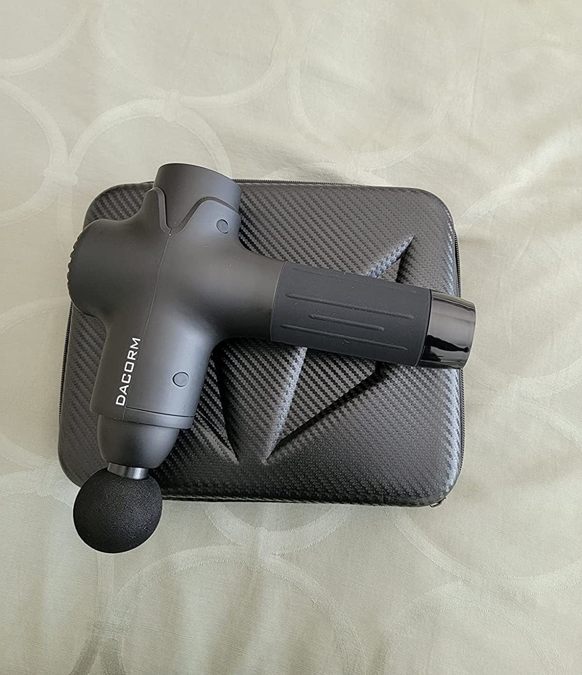 reviewer image of the massage gun on top of its case