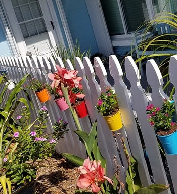 reviewer photo of the colorful planters hanging on a white picket fence
