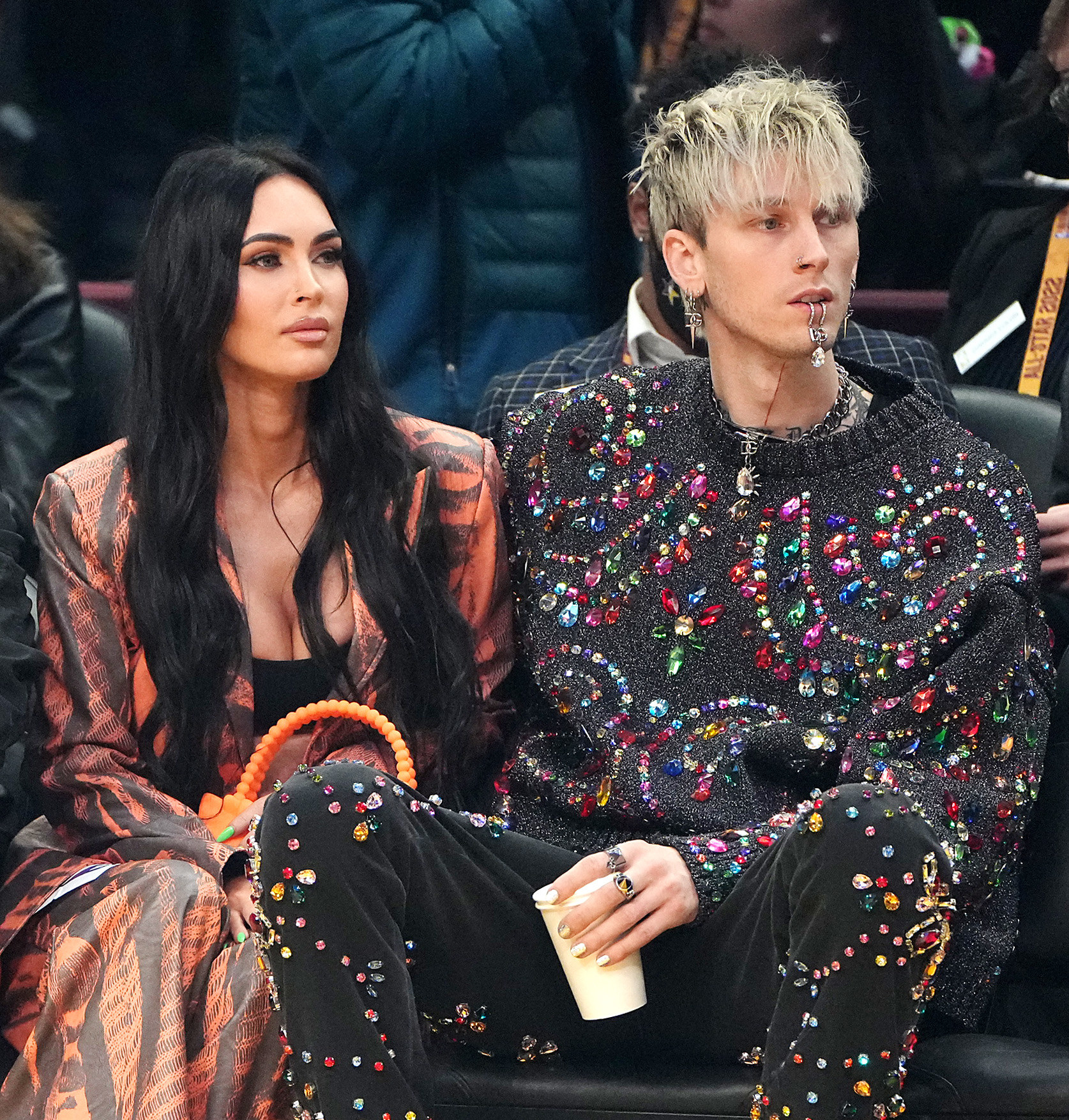 Megan and MGK sitting and watching a sports activity in a stadium