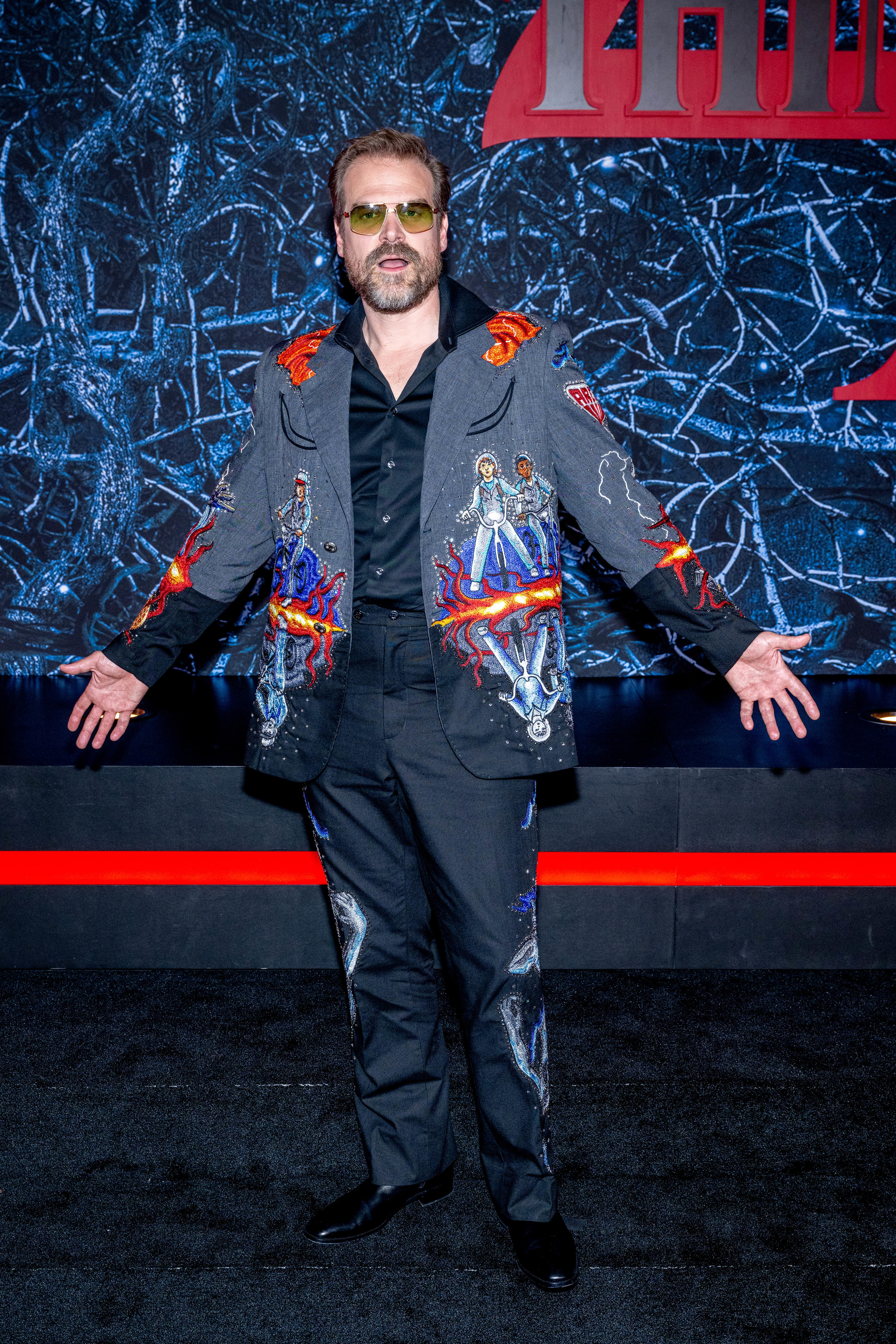 David in a wildly different outfit; this time, it&#x27;s a custom suit colorfully emblazoned with images from Stranger Things