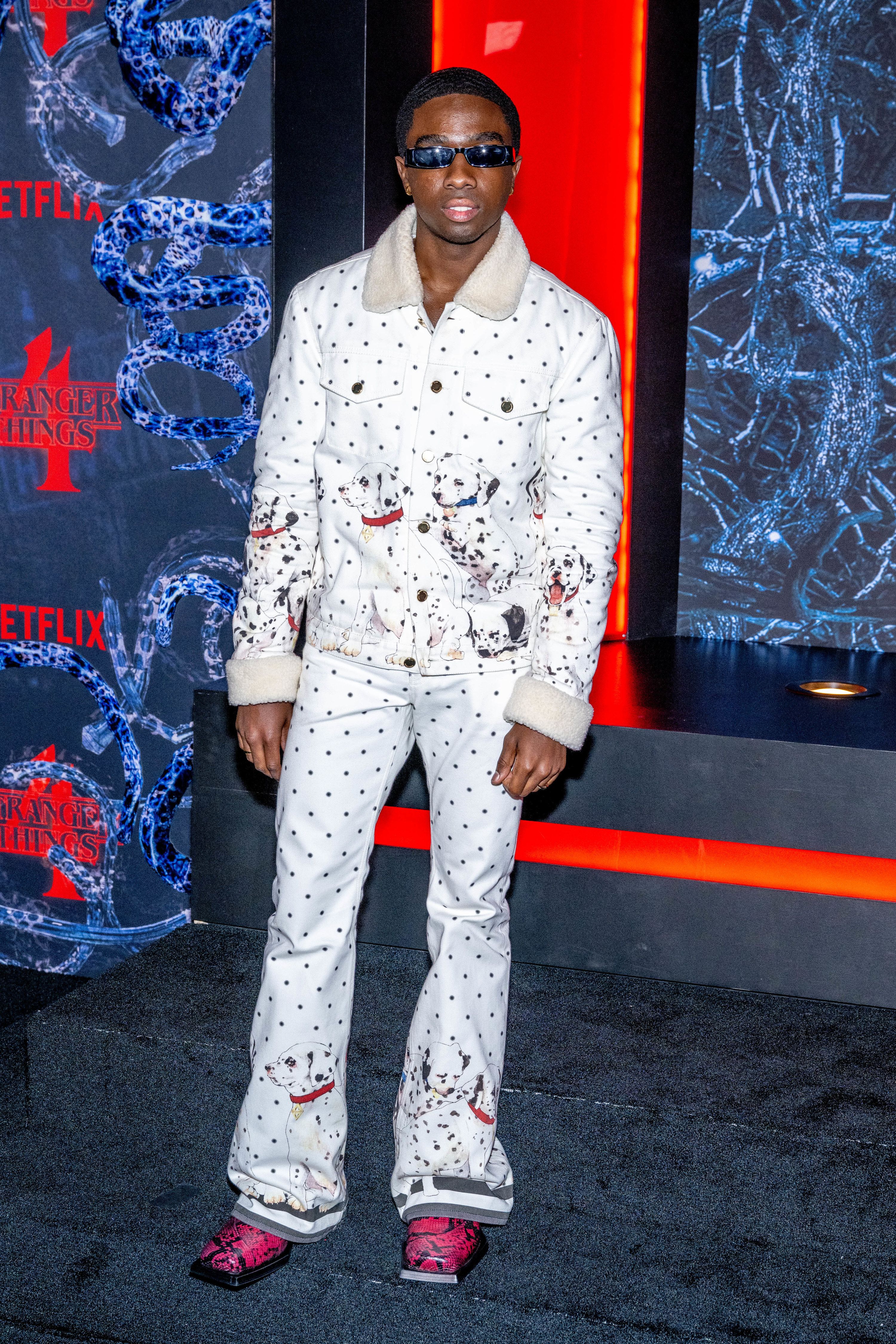 Caleb looking much older and wearing sunglasses, a polka dot suit with Dalmatians on it, and bellbottom pants with bright red and black shoes