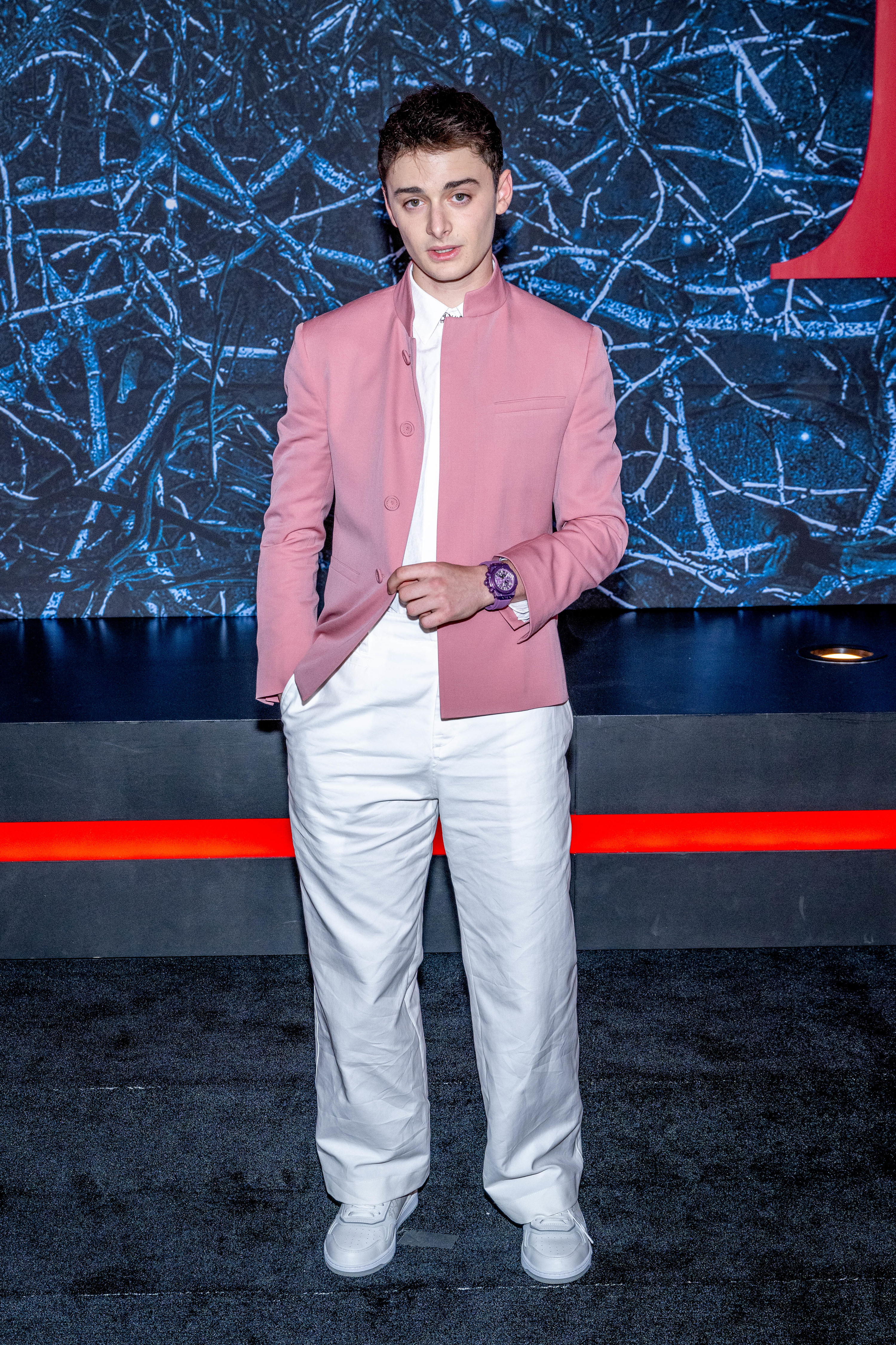 诺亚看起来更年长、更时尚,白色的裤子,一个粉红色的外套,和一个大的手表