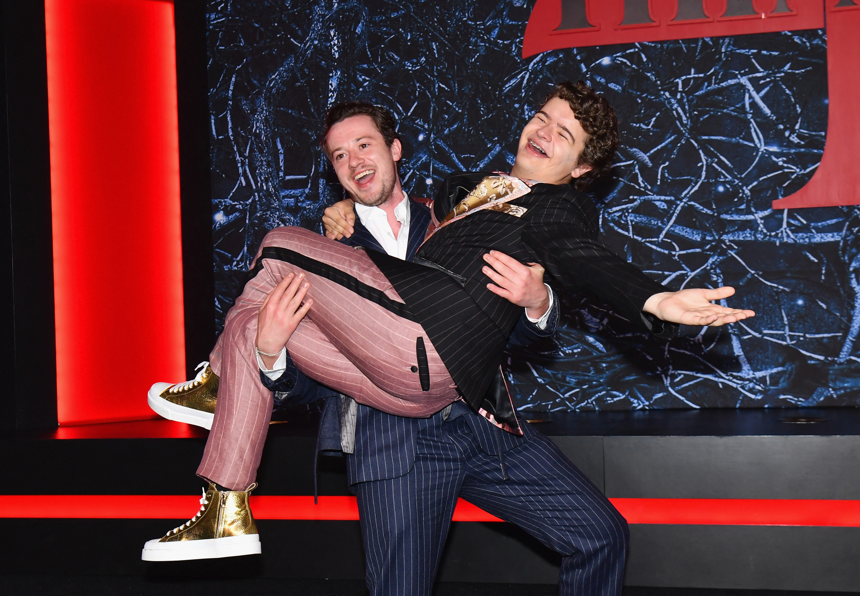 Gaten laughing while being carried on the red carpet