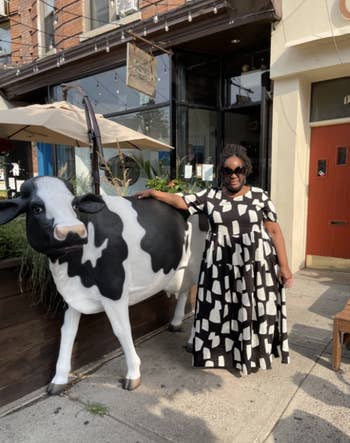 reviewer standing outside cow cafe decor in black and white dress