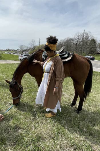 reviewer wearing the dress in a layered look while standing beside a horse