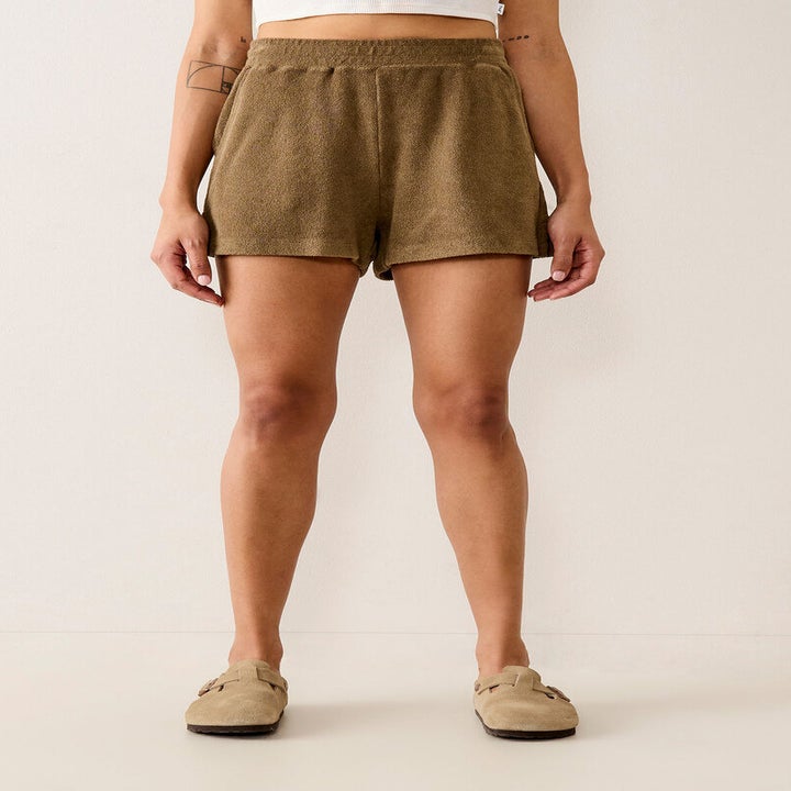 A person wearing the shorts with clogs and a crop top