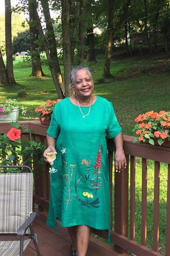 reviewer wearing the dress in green with gardening shoes