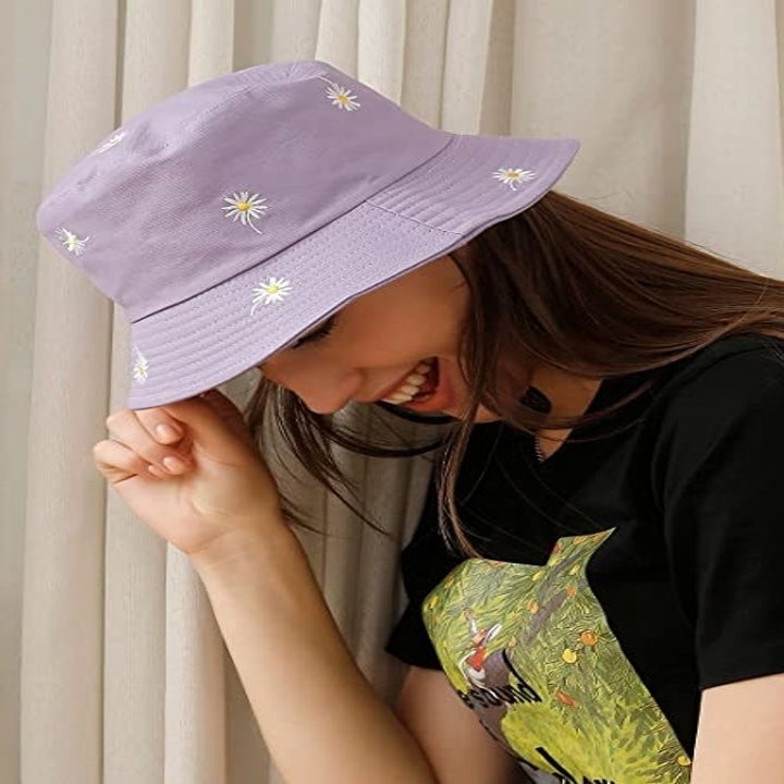 A person holding the brim of the bucket hat