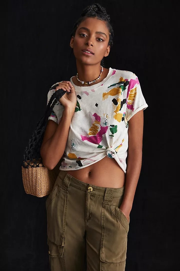 A model wearing the tee, knotted at the hem, in the color Neutral Motif