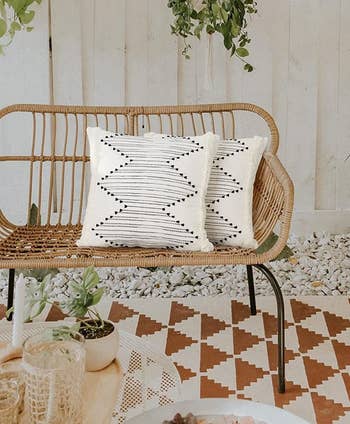 the pillow covers on two pillows, which are on a wicker patio seat