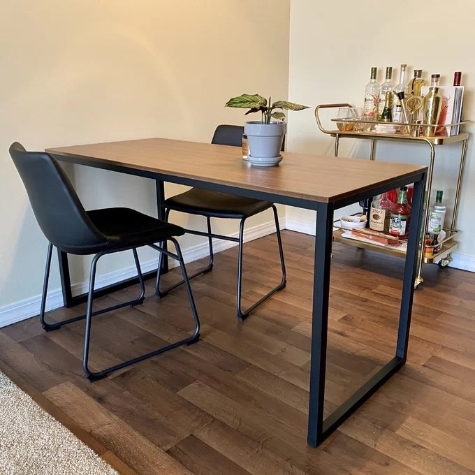 A wooden dining table with metal legs, surrounded by two dining chairs