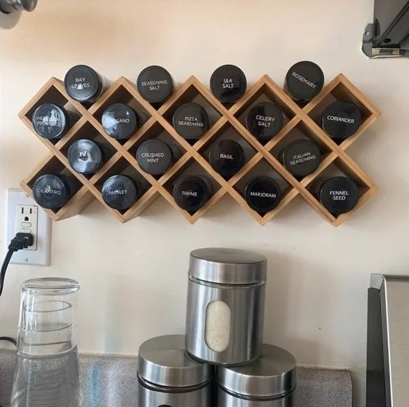 A criss cross wooden spice rack with 18 labeled jars