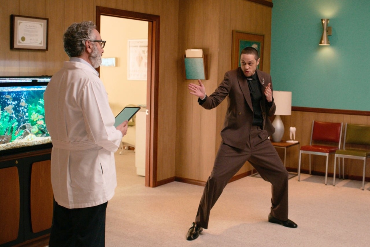 Hombre en traje  con pose rara frente a un doctor