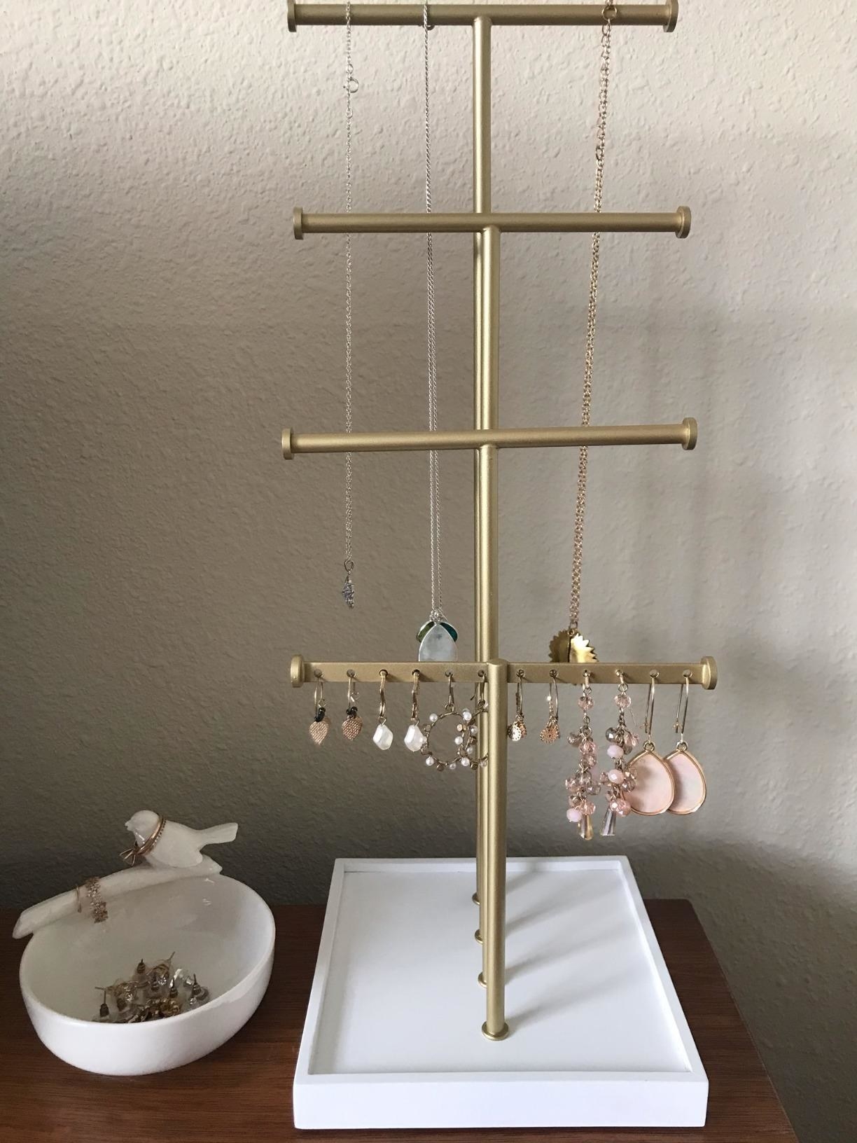 a reviewer&#x27;s jewelry stand in white and gold