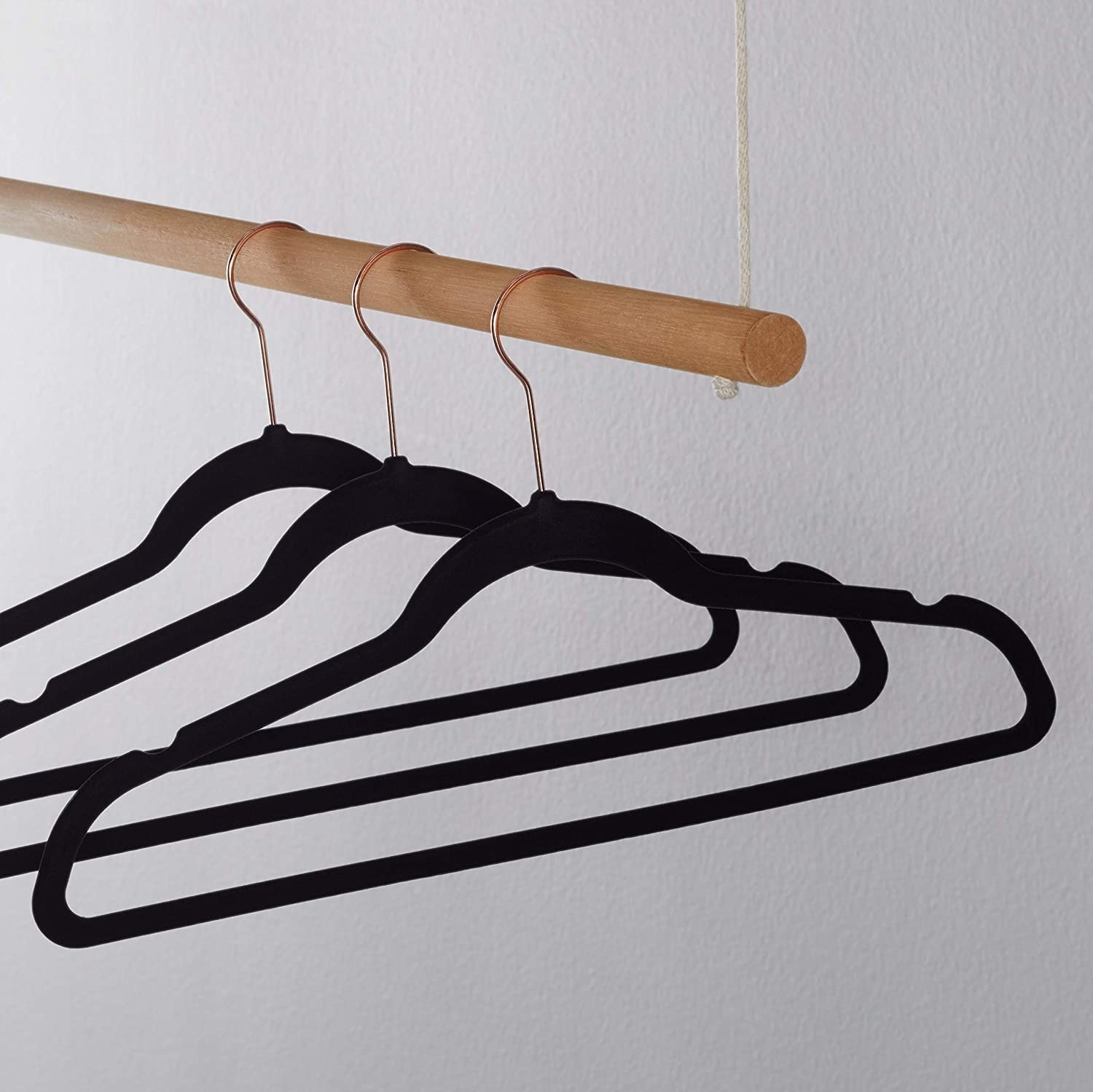 Three velvet hangers on a clothing rod