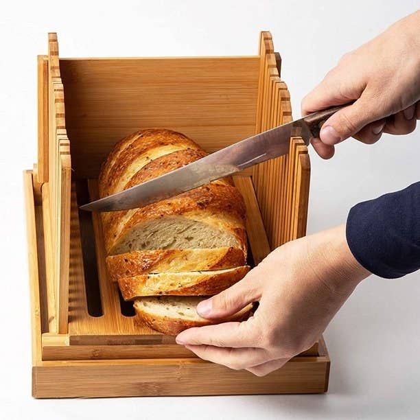 Model is slicing a baguette in the bread cutter