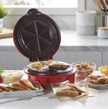 The quesadilla maker in red surrounded by various foods