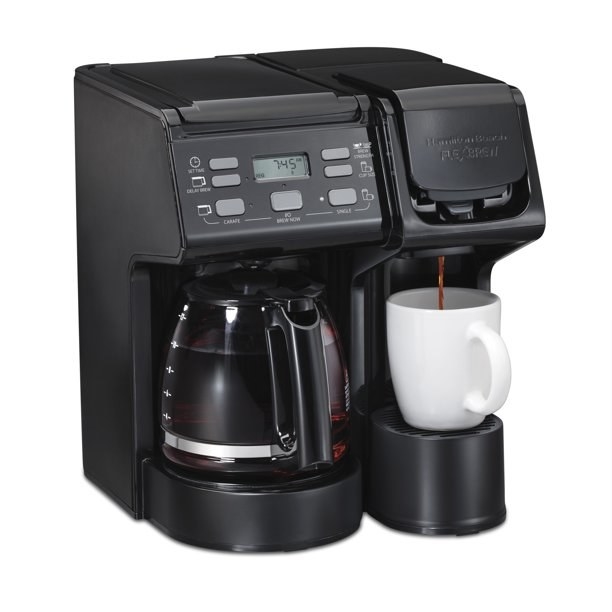 The coffee maker with coffee in the pot and a mug