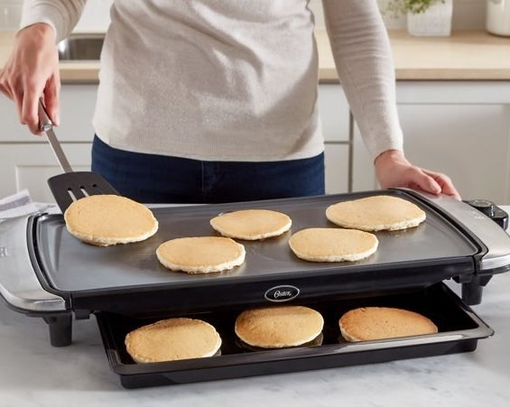 Model is flipping pancakes on the black electric griddle