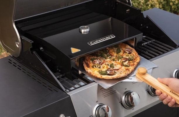 A pizza oven kit for a grill and a pizza coming out of it