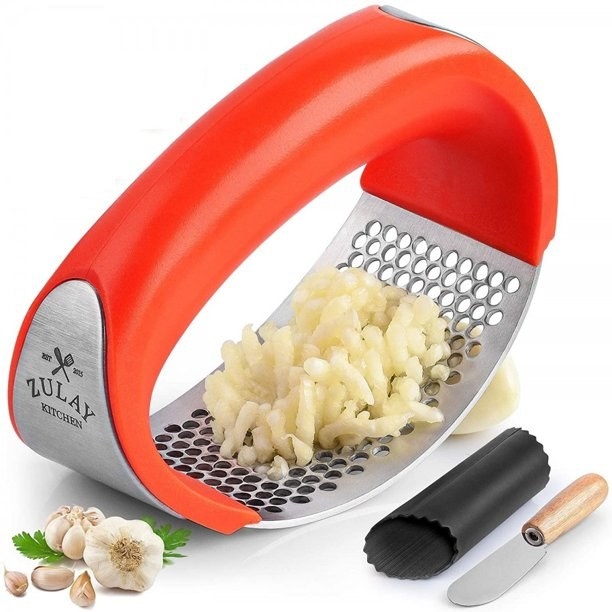 The garlic press in chrome and bright orange with garlic minced on it