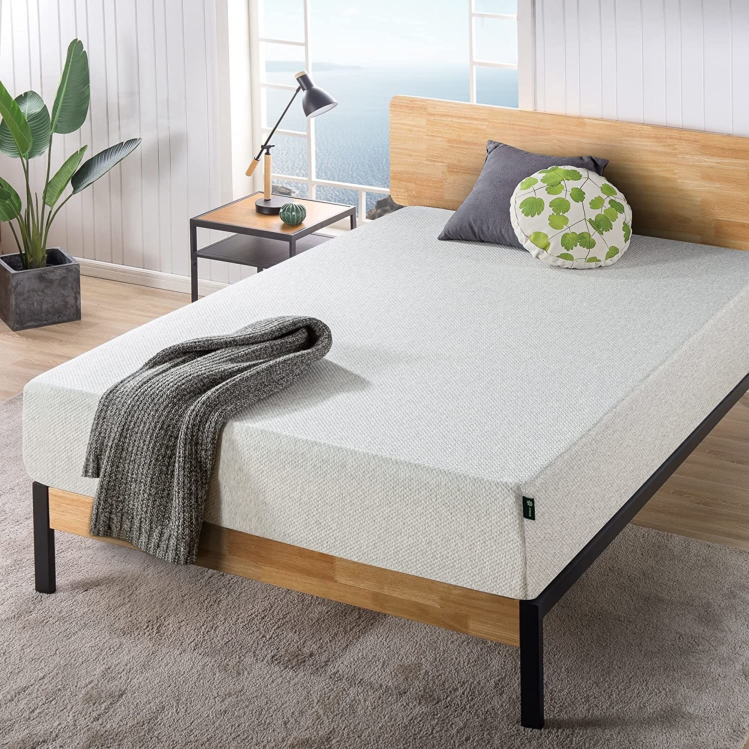 The mattress on a platform bedframe with two cushions and a throw on it