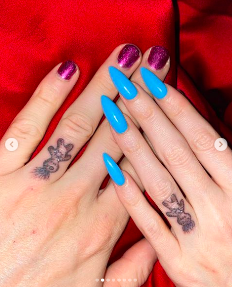 An image of Megan and MGK&#x27;s left hands, each with a matching tattoo of an upside down voodoo doll on the ring finger