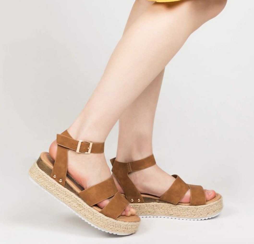 A model wearing a pair of brown two strap platform sandals