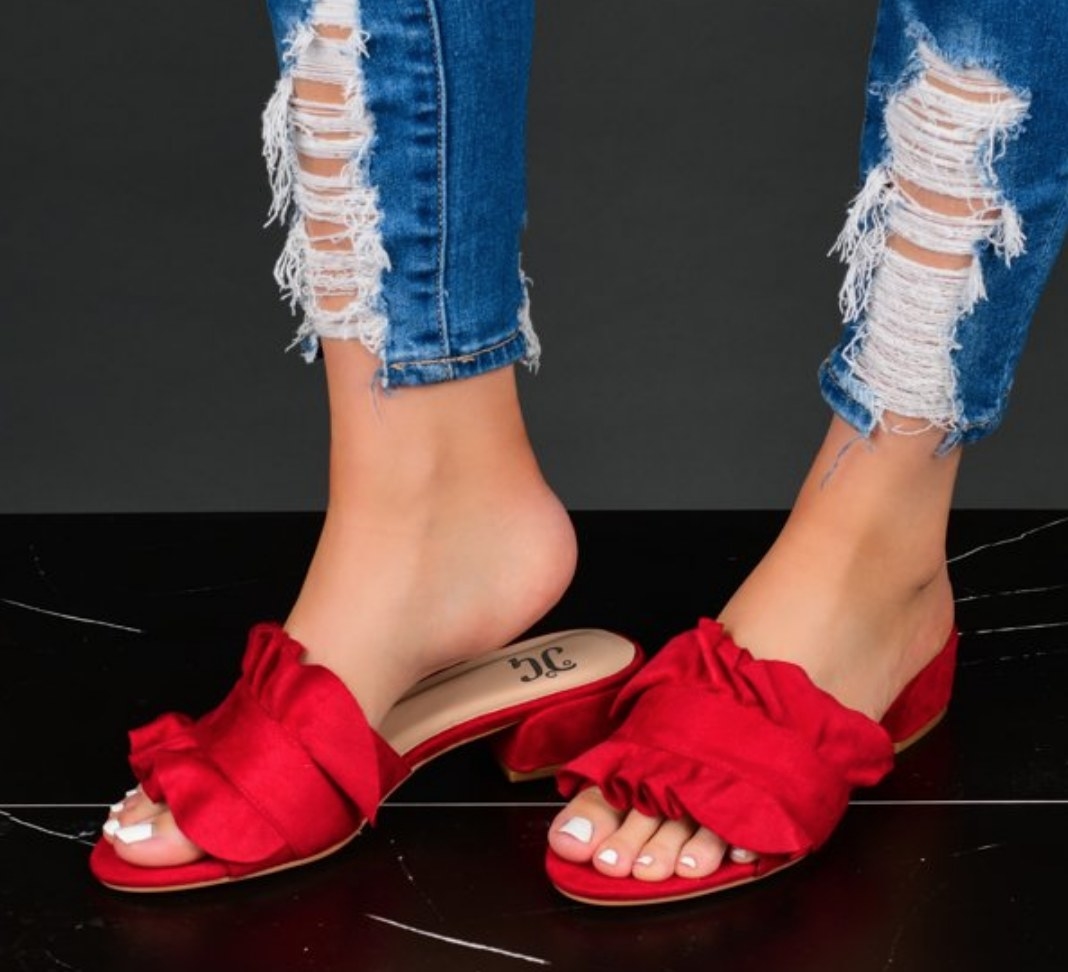A model wearing a pair of ruffled red mules