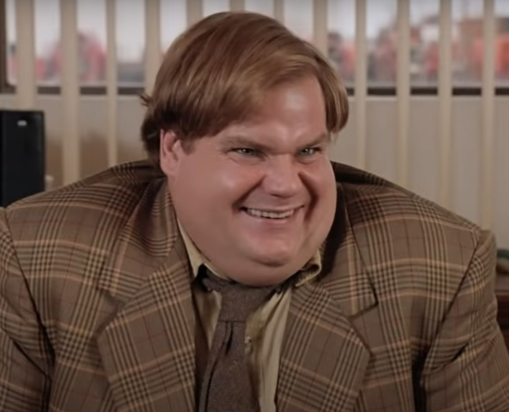 Chris Farley as Tommy laughs after he tells a joke during a work meeting