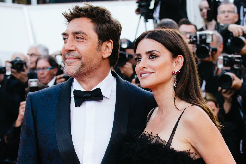 Javier Bardem and Penelope Cruz at an event as paparazzi stand behind them