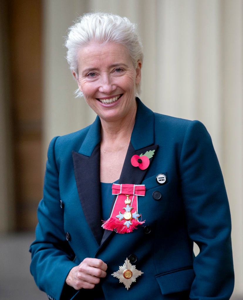 Emma Thompson smiles and wears medals and pins on her blazer